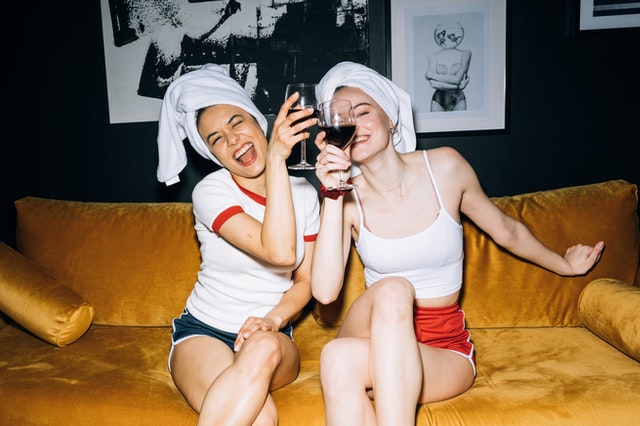2 women drinking wine with towels on their heads laughing